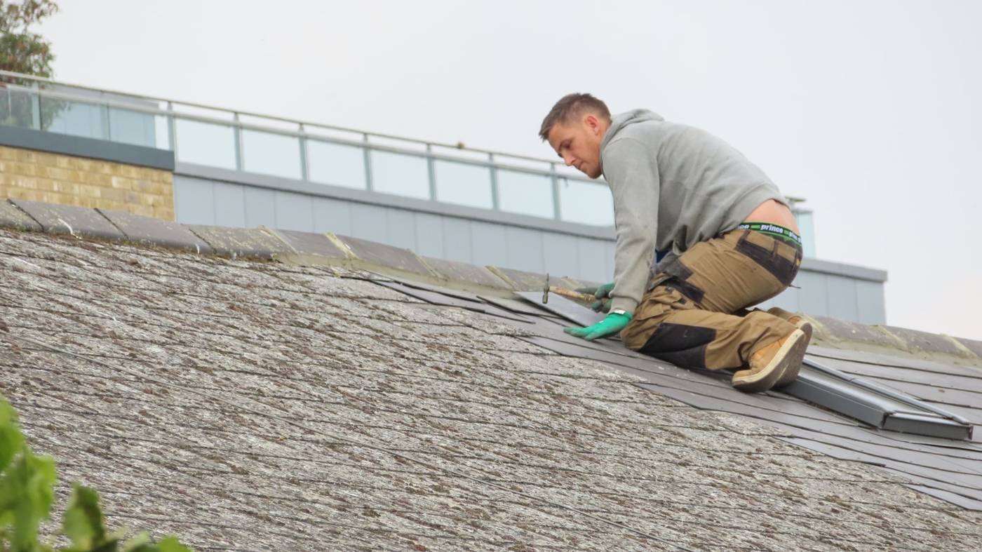 Couvreur au travail sur une toiture en cours de réfection