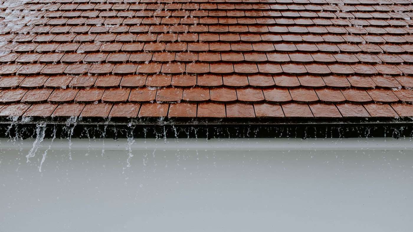 Pluie battante sur un toit en tuiles et sa gouttière