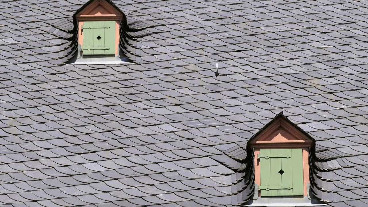 Toit en ardoise naturelle avec deux lucarnes à volets verts